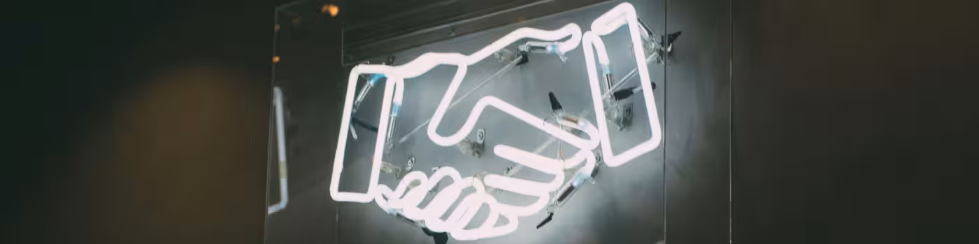 Ein Neon-Schild mit einem Handschlag darauf.